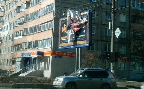 На ул. Октябрьской над дорогой развевается оторвавшийся кусок рекламной вывески